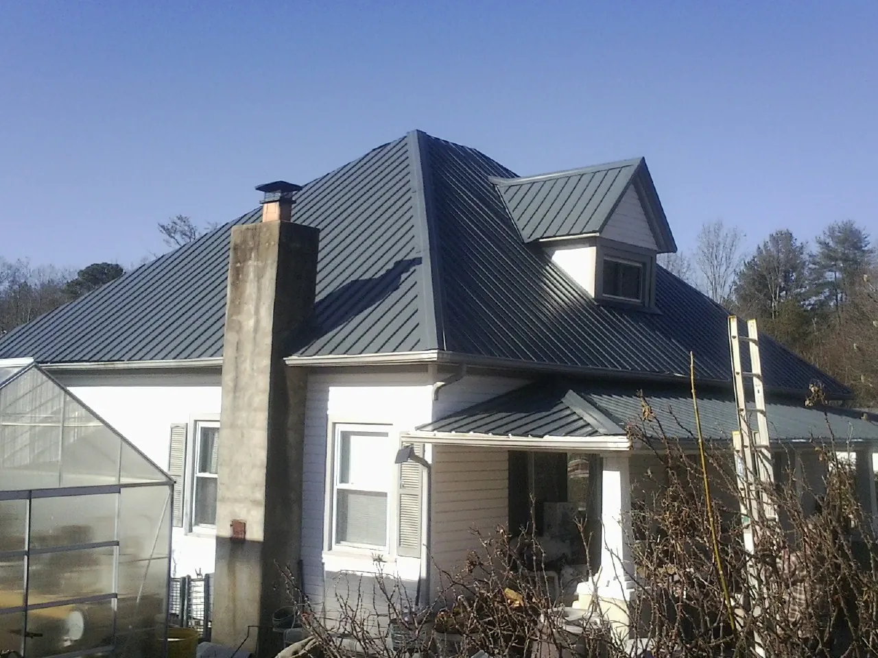 Dark blue standing seam metal roof on a white farmhouse with dormer — Slate & Tile Roof Repair by Roofing Brothers in Pottsville