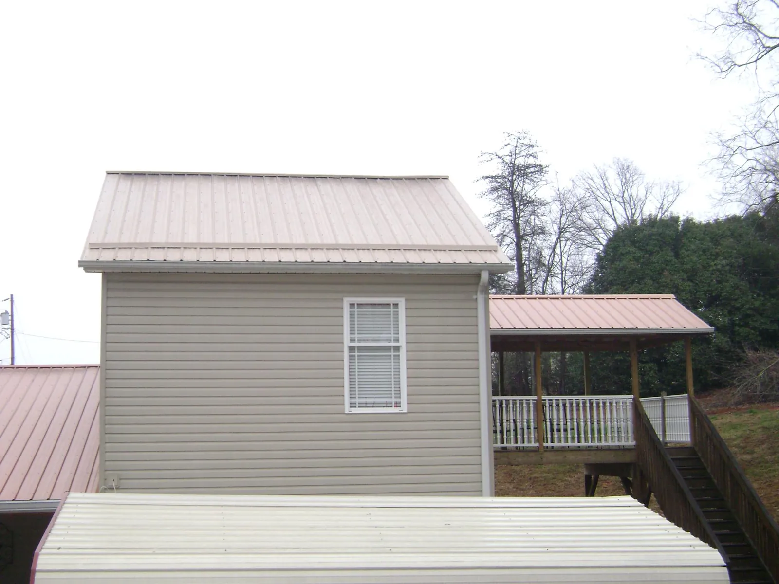 Tan metal roofs on a two story addition and attached porch, from a Roof Replacement job in Pottsville
