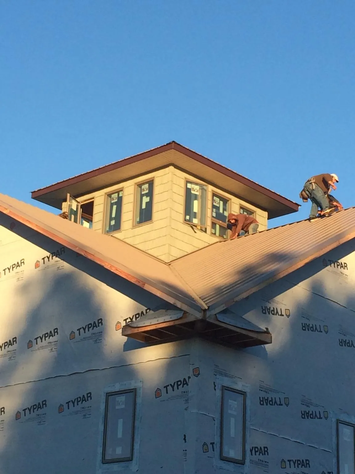Roofers working around a rooftop cupola on a new metal roof at sunset — Roof Waterproofing in Pottsville by Roofing Brothers